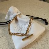 The Blake Bracelet, a waterproof gold paperclip chain bracelet with pavé T-bar toggle, laid on The Seventh Edit’s branded white pouch.