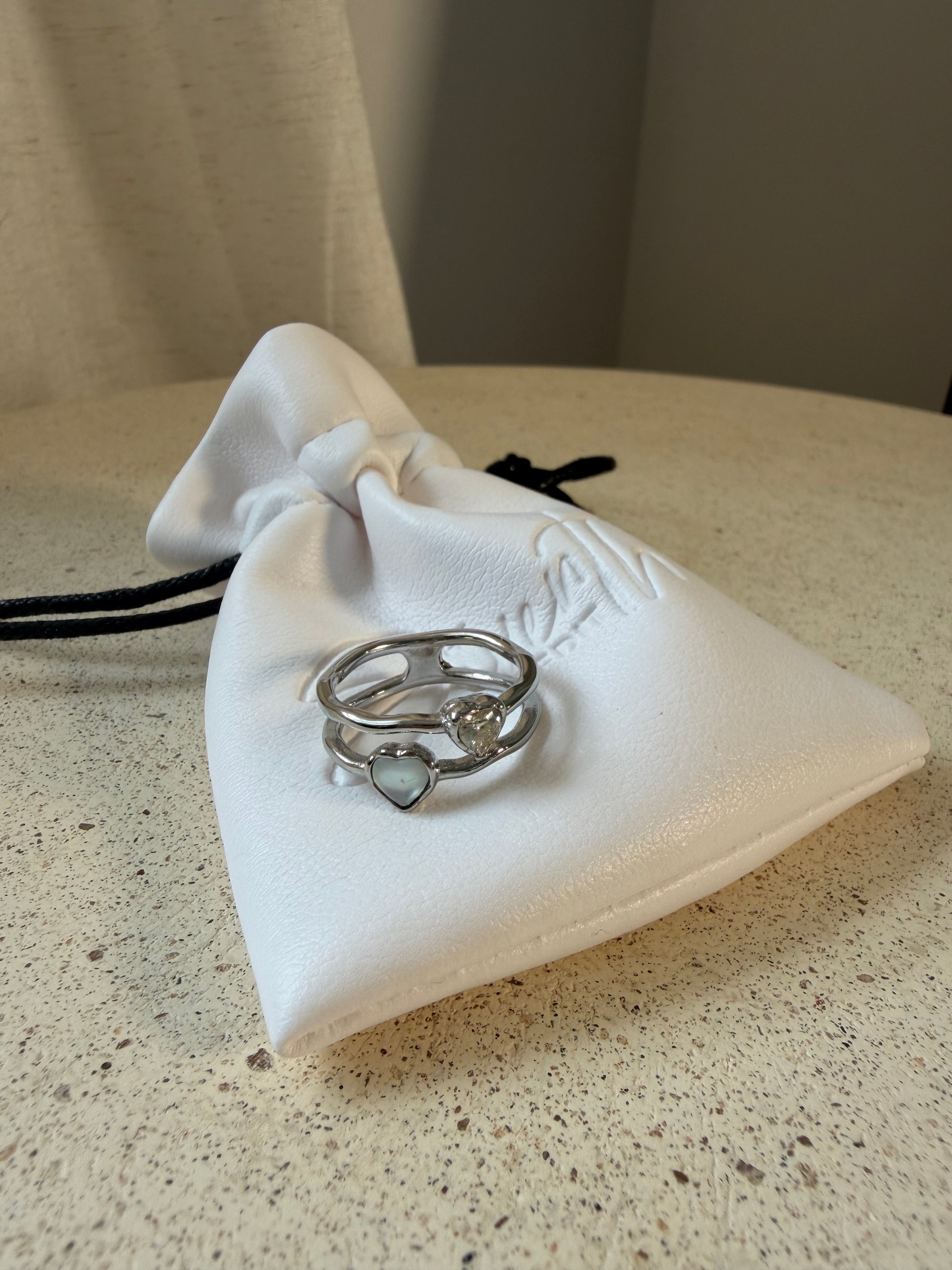 The Isla Ring  stacking rings with mother-of-pearl heart and stone detail, laid on The Seventh Edit’s branded white pouch.